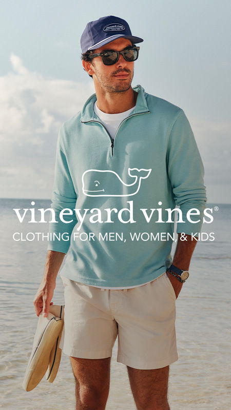 A man on the beach wearing a light blue pullover and shorts.