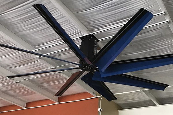 Blue HVLS Fan hanging from office ceiling.