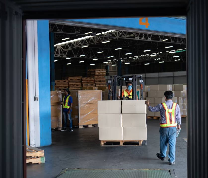 Forklift pulling pallets out of the back of a freight truck