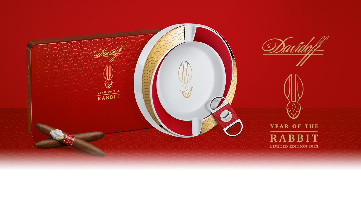 Two Davidoff Year of the Rabbit Limited Edition cigars crossed lying in front of their red box, next to them are the Year of the Rabbit ashtray and the Year of the Rabbit cutter.