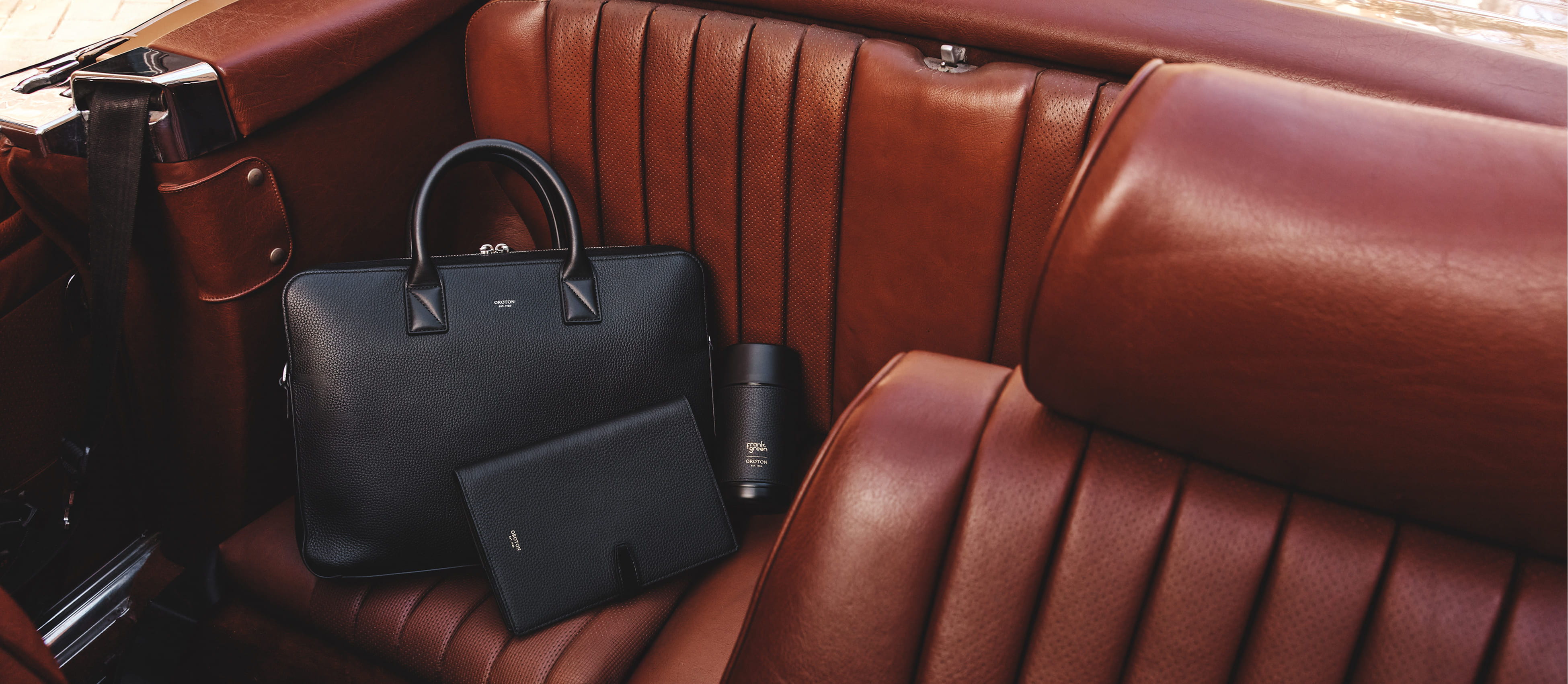 A leather interior with a black bag and accessories on the seat.