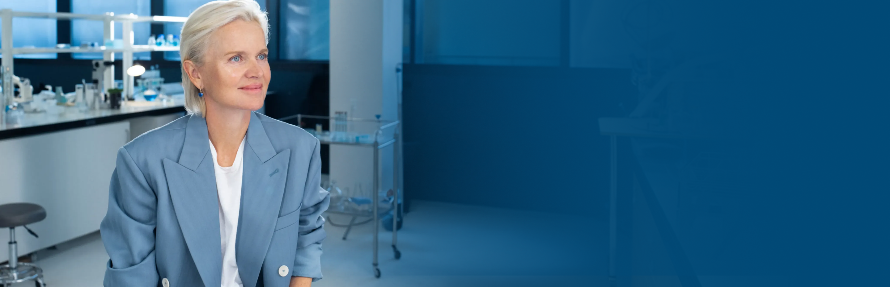A woman in a lab coat smiling in a laboratory setting.