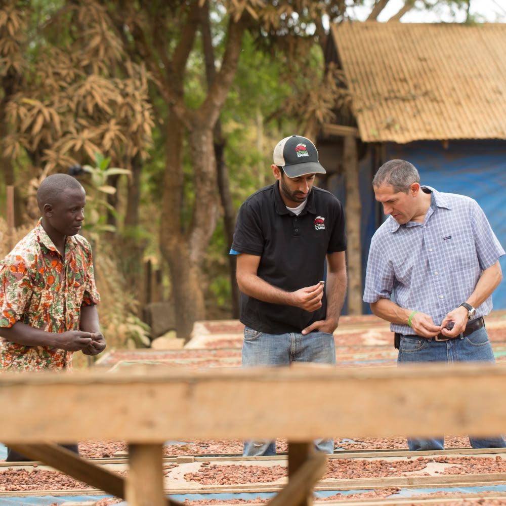 Three men examining materials outdoors near a building under construction.