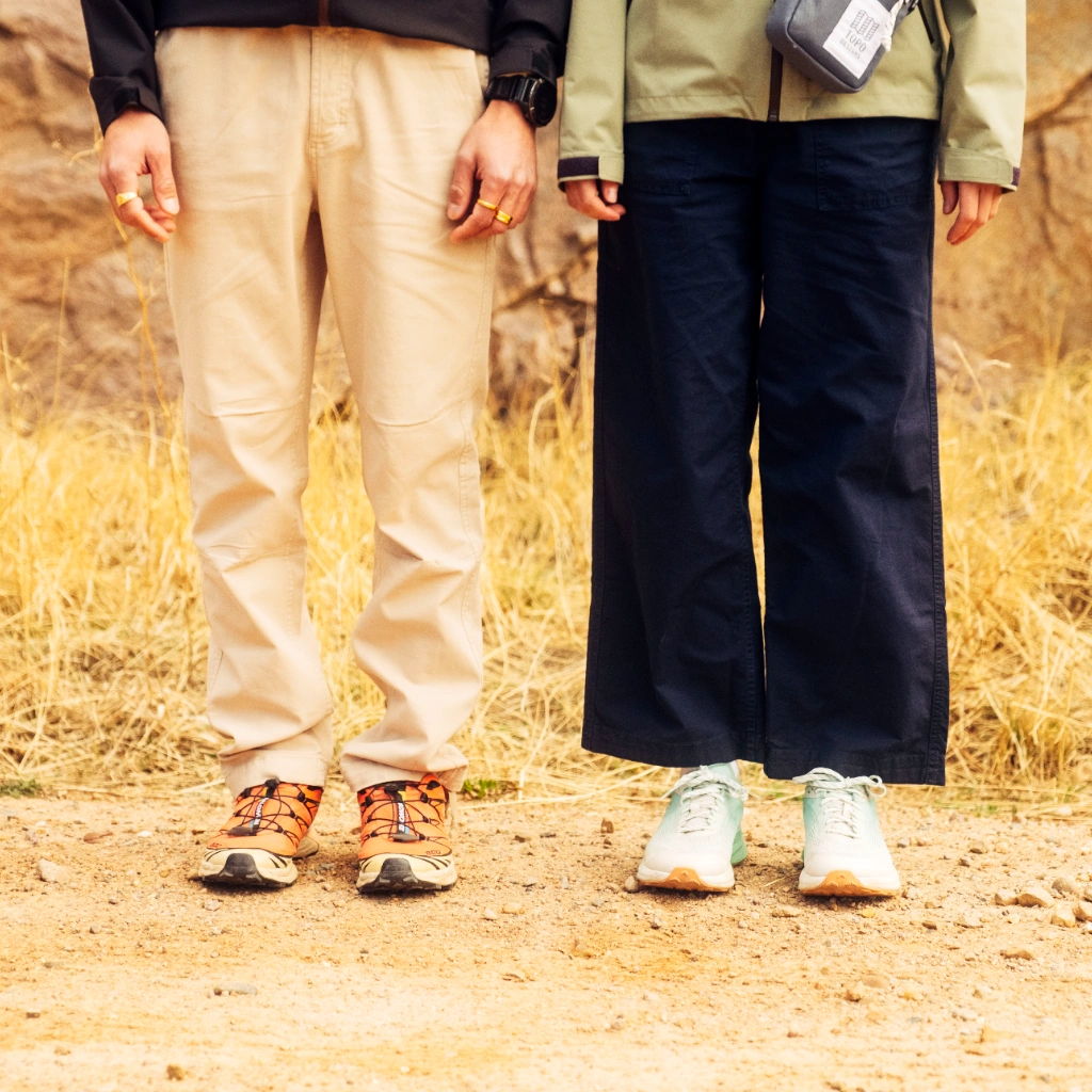 Two people standing side by side, wearing different pants and shoes.