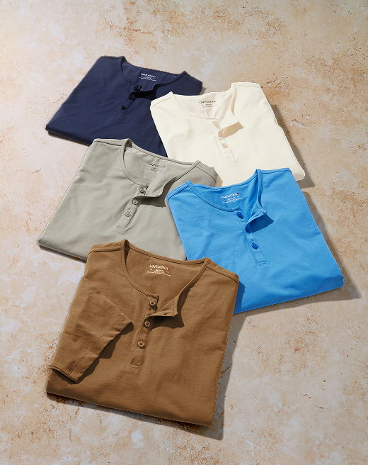 Five folded shirts in various colors arranged on a flat surface.