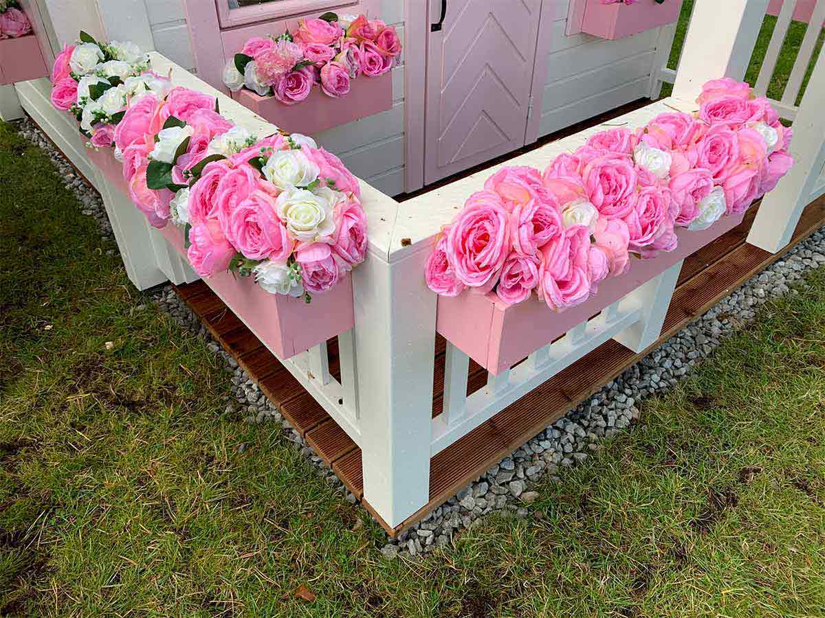 2-Story Outdoor Playhouse Princess close up of the wooden porch with white railing with pink flower boxes and flowersby WholeWoodPlayhouses