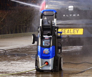 A blue and black pressure washer in action, spraying water.
