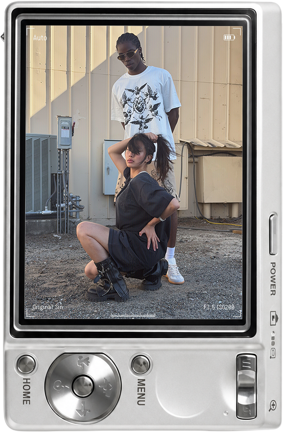 Two people posing in front of a building, one crouching and one standing.
