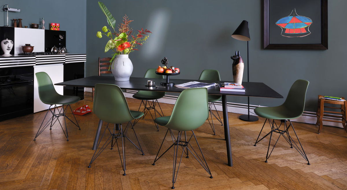Modern Vitra dining room with a black table and green DSW chairs, featuring decorative elements.