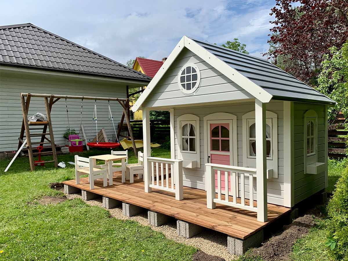 Custom Playhouse with white flower boxes pink door and spacious wooden terrace by WholeWoodPlayhouses