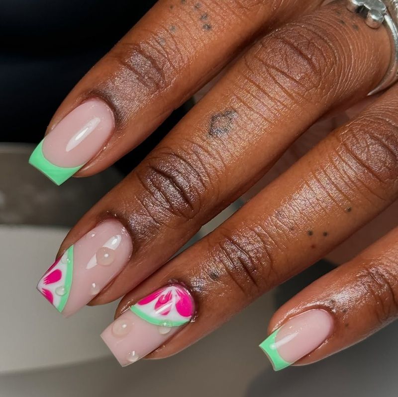 Close-up of manicured nails with green tips and pink floral design.