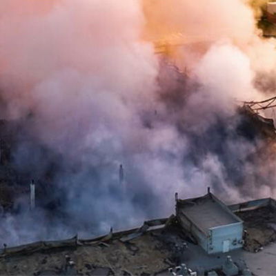 Smoke rising from a damaged area, with a building partially visible.