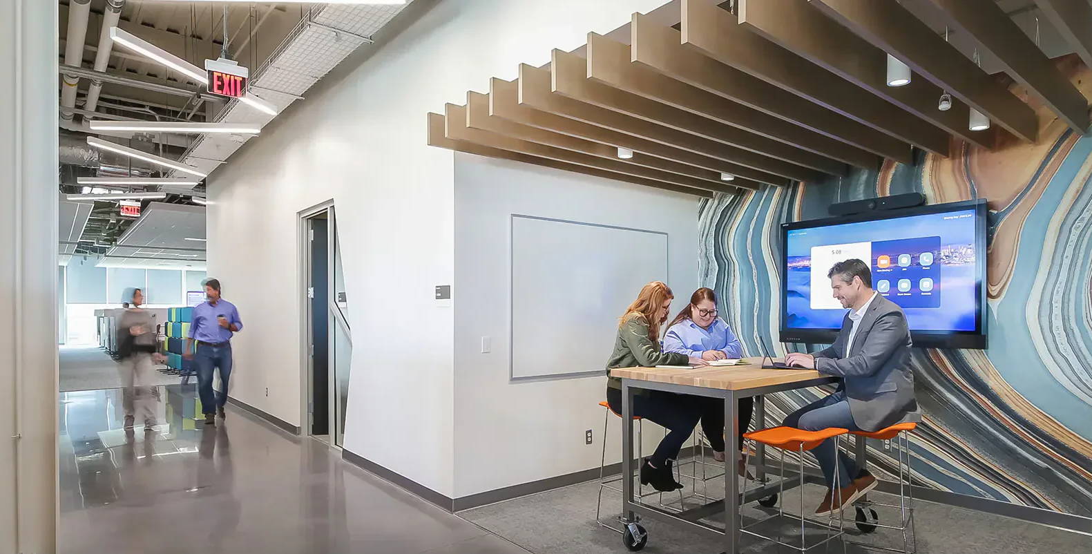 Modern office space with collaborative work areas and colorful wall design.