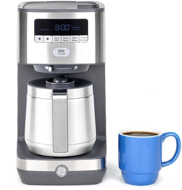 Coffee maker with a stainless steel carafe and a blue mug of coffee.