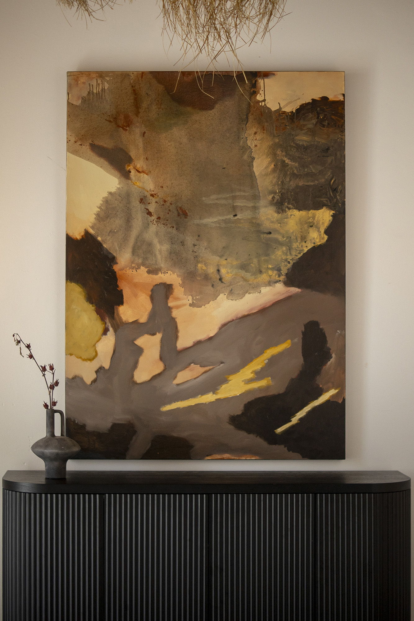 Abstract painting 'Undertow' from Stephen Skinner on wall above a dark wooden cabinet with decorative vase.