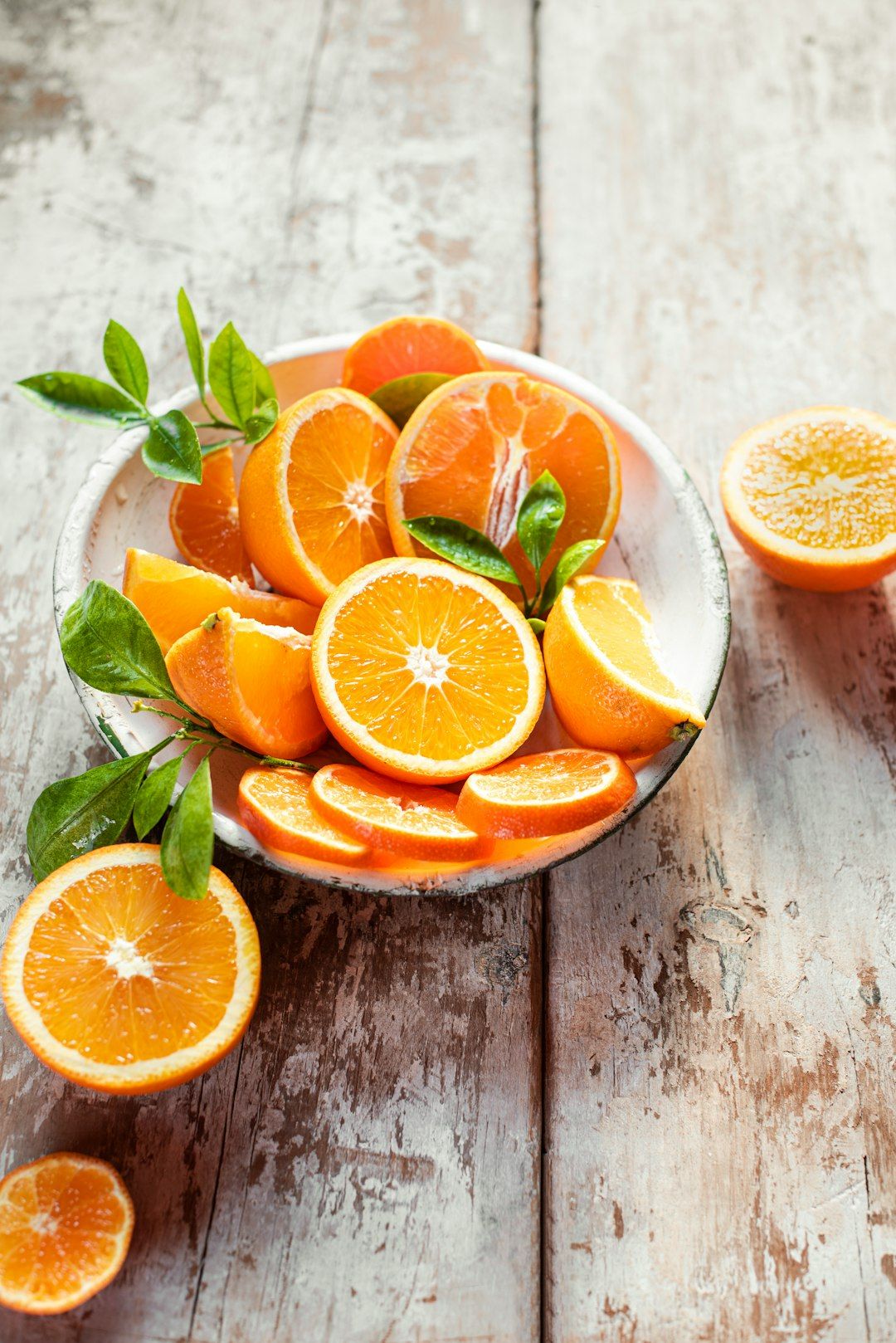 a bowl of sliced oranges on a wooden table