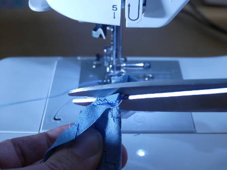 Cutting of the tip of a sewn fabric piece to make a mitered corner