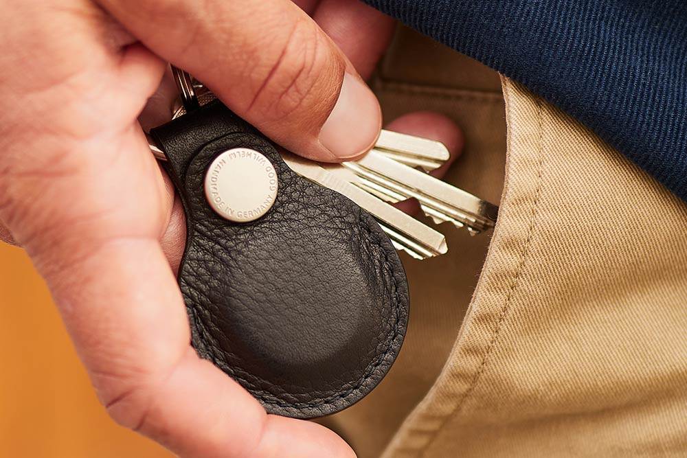 Ein Mann steckt einen Airtag Schlüsselanhänegr aus Leder in seine Hosentsche