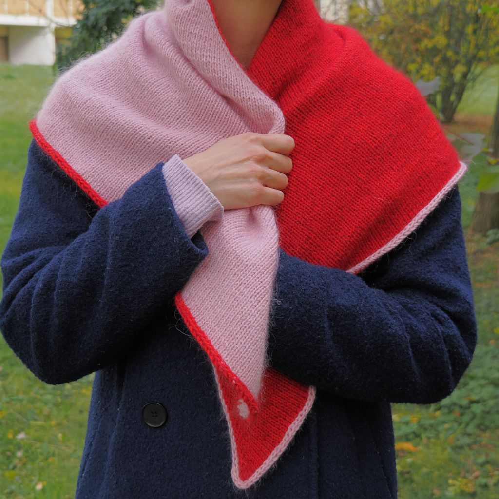 Person die ein rosa-rotes Dreieckstuch über dem Mantel trägt.