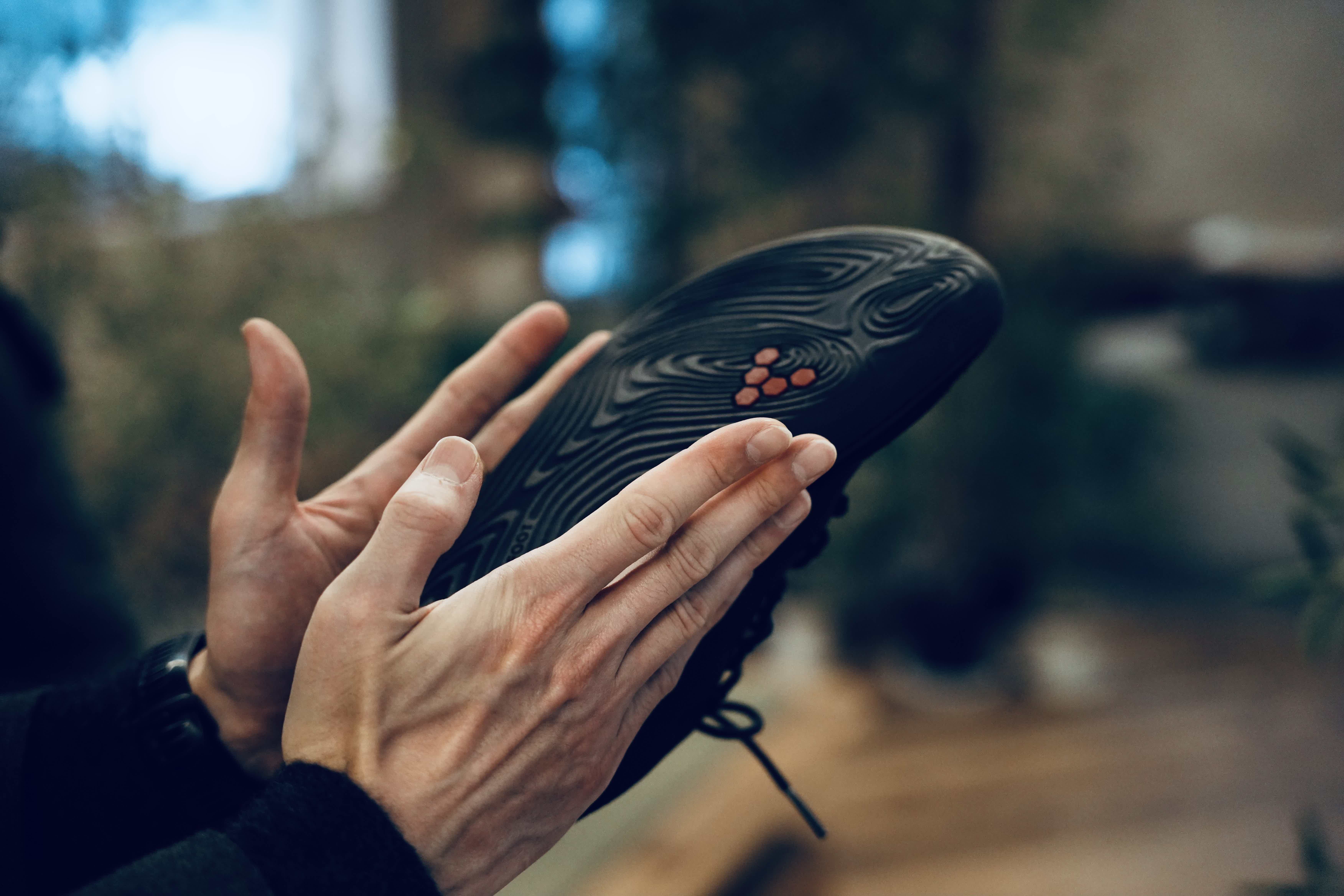 A person holding a shoe with a black sole and red details.