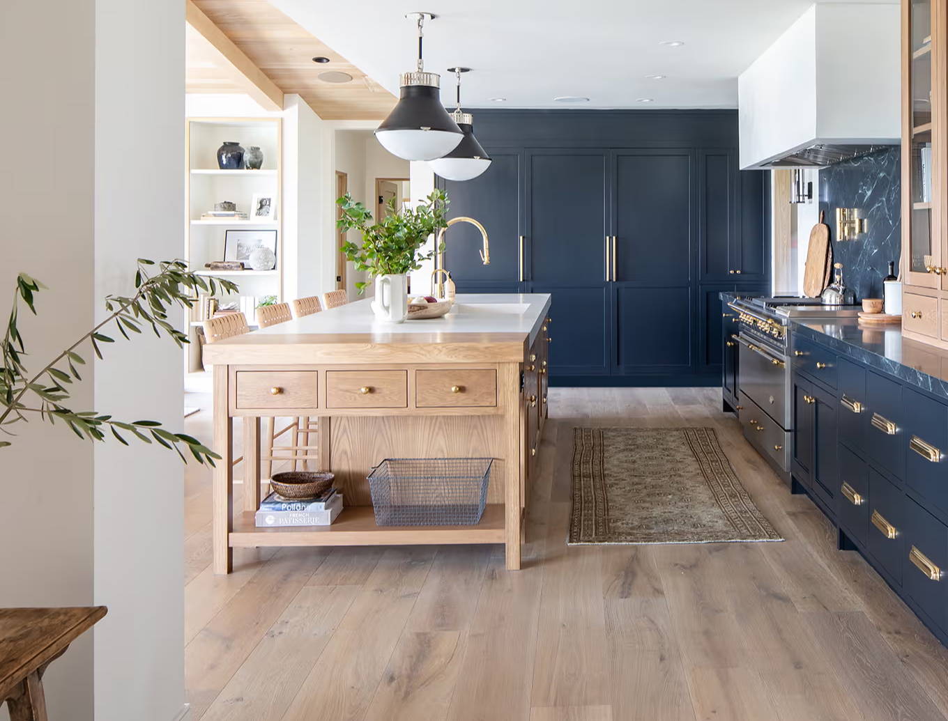 Navy and oak kitchen with brass hardware, wood flooring and marble worktops