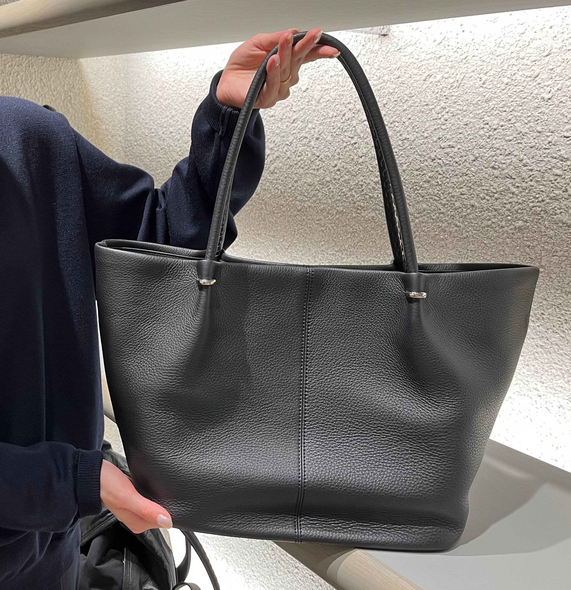 Person holding a black handbag in a well-lit store.