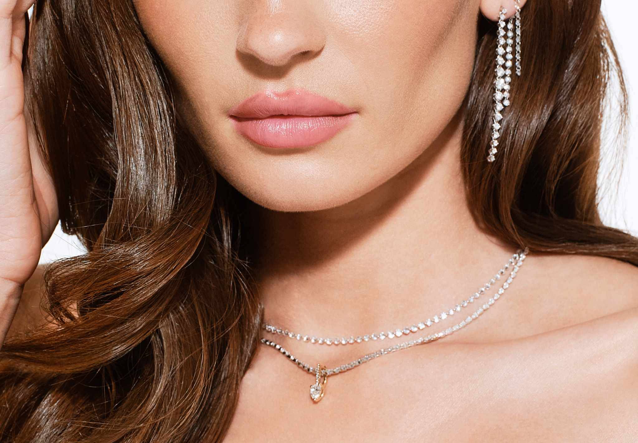 Woman with long hair wearing elegant jewelry, looking directly at the camera.