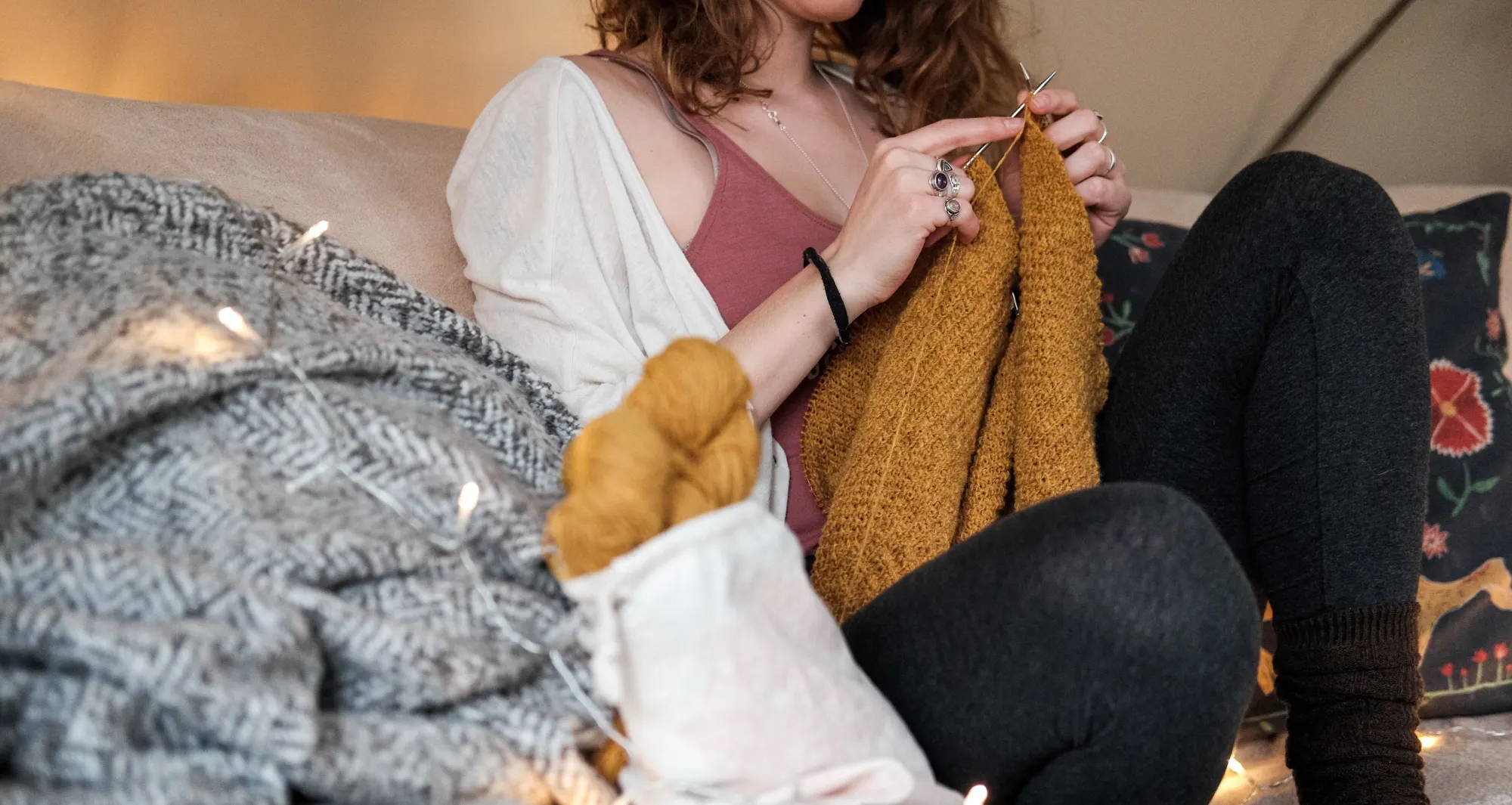 Woman knitting with hemp yarn on a couch.