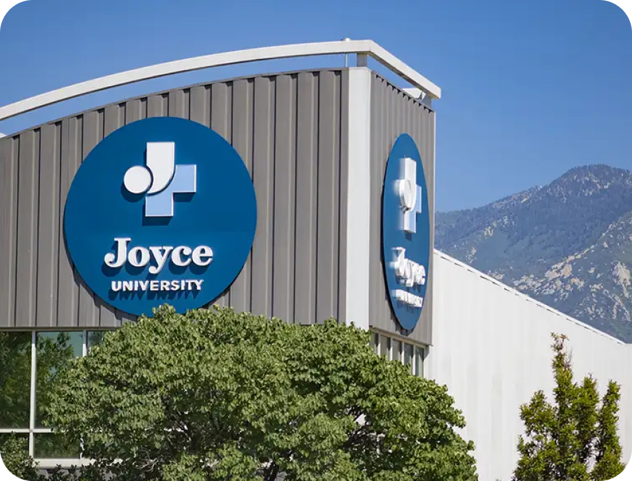 Signage of Joyce University on a building with mountains in the background.