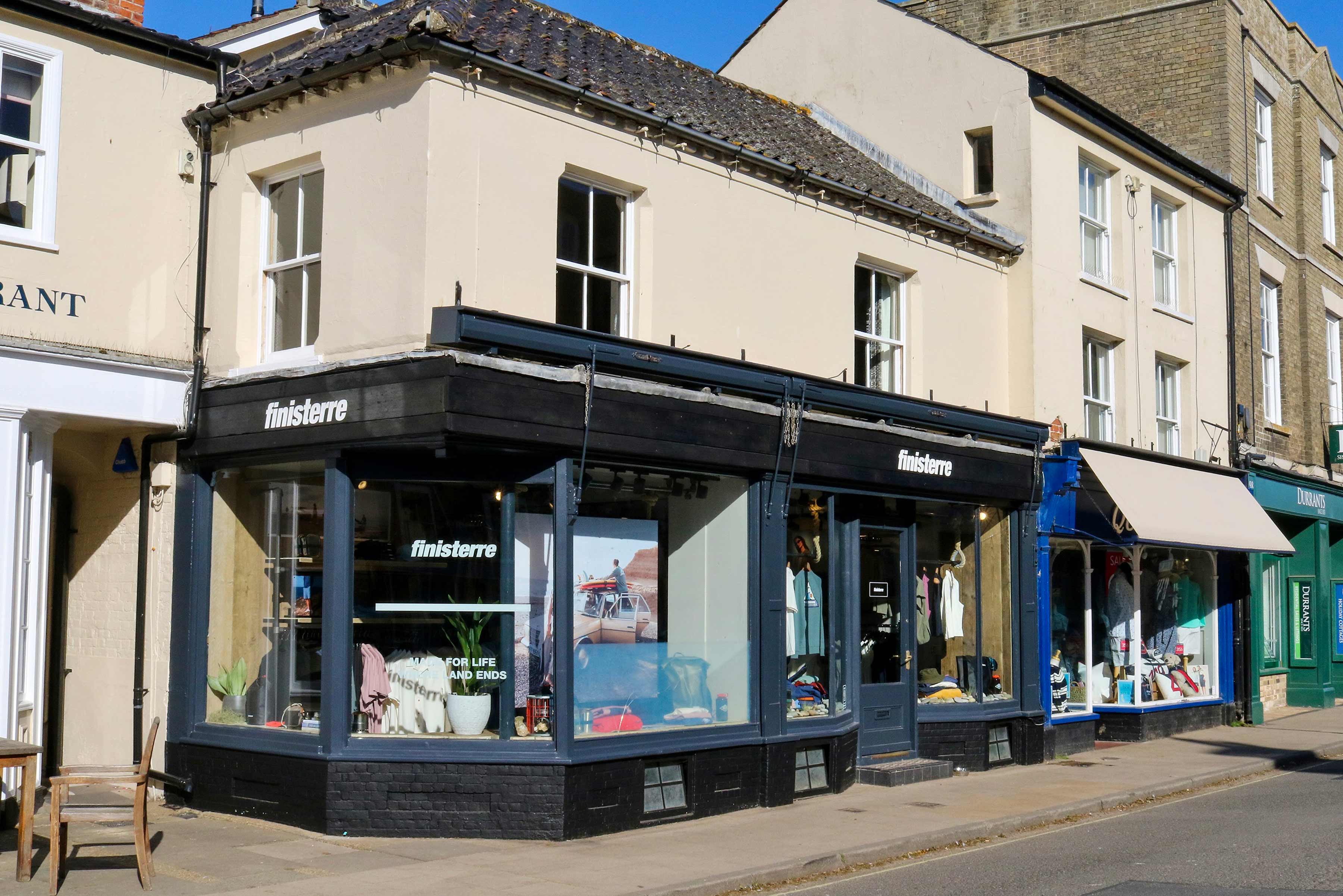 A storefront with large windows and colorful displays on a sunny day.