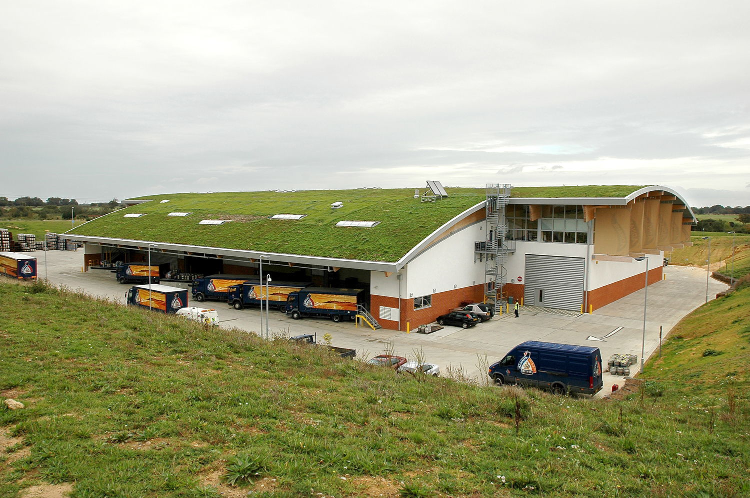 Completed Adnams Distribution Centre from above with drays and whole grass roof and building in view.
