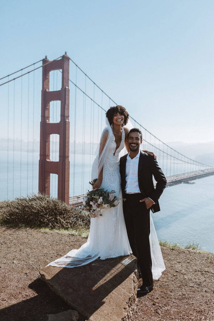 Die Braut im Chelo-Kleid mit ihrem Bräutigam mit Blick auf die Golden Gate Bridge