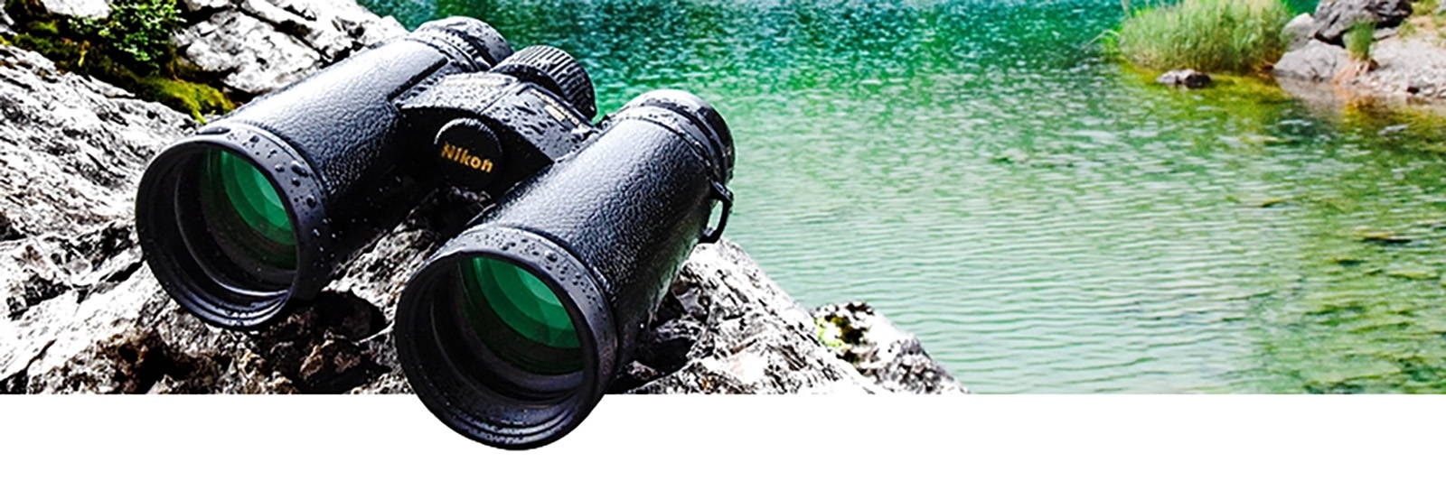A pair of Nikon binoculars overlaid on a lake with rocky banks