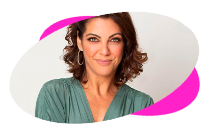 A woman with curly hair smiling, wearing a green blouse against a light background.