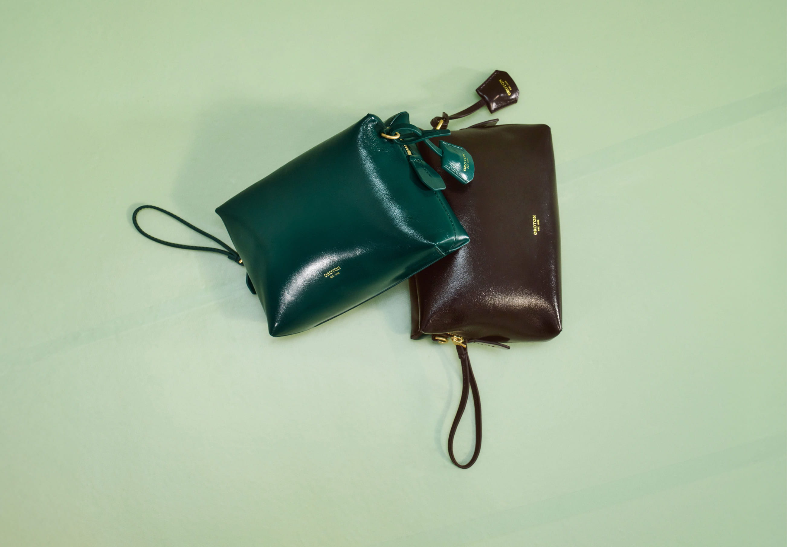 Two handbags, one green and one brown, placed on a light background.