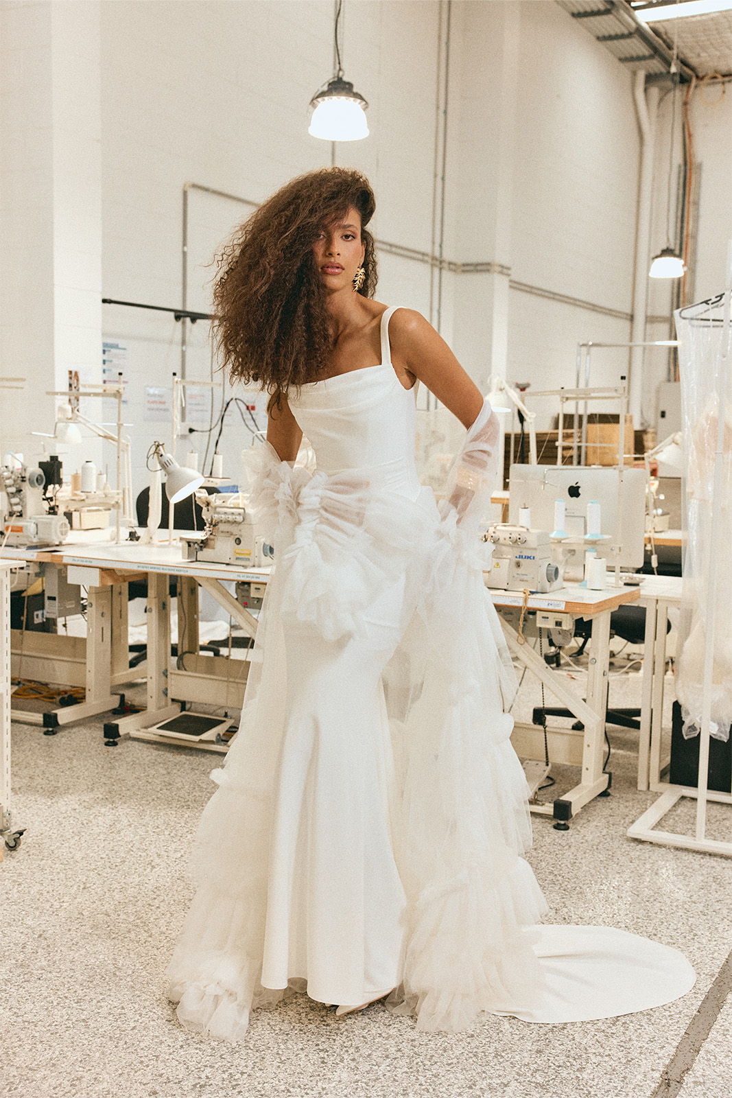 Woman in a white dress poses in a clothing workshop.