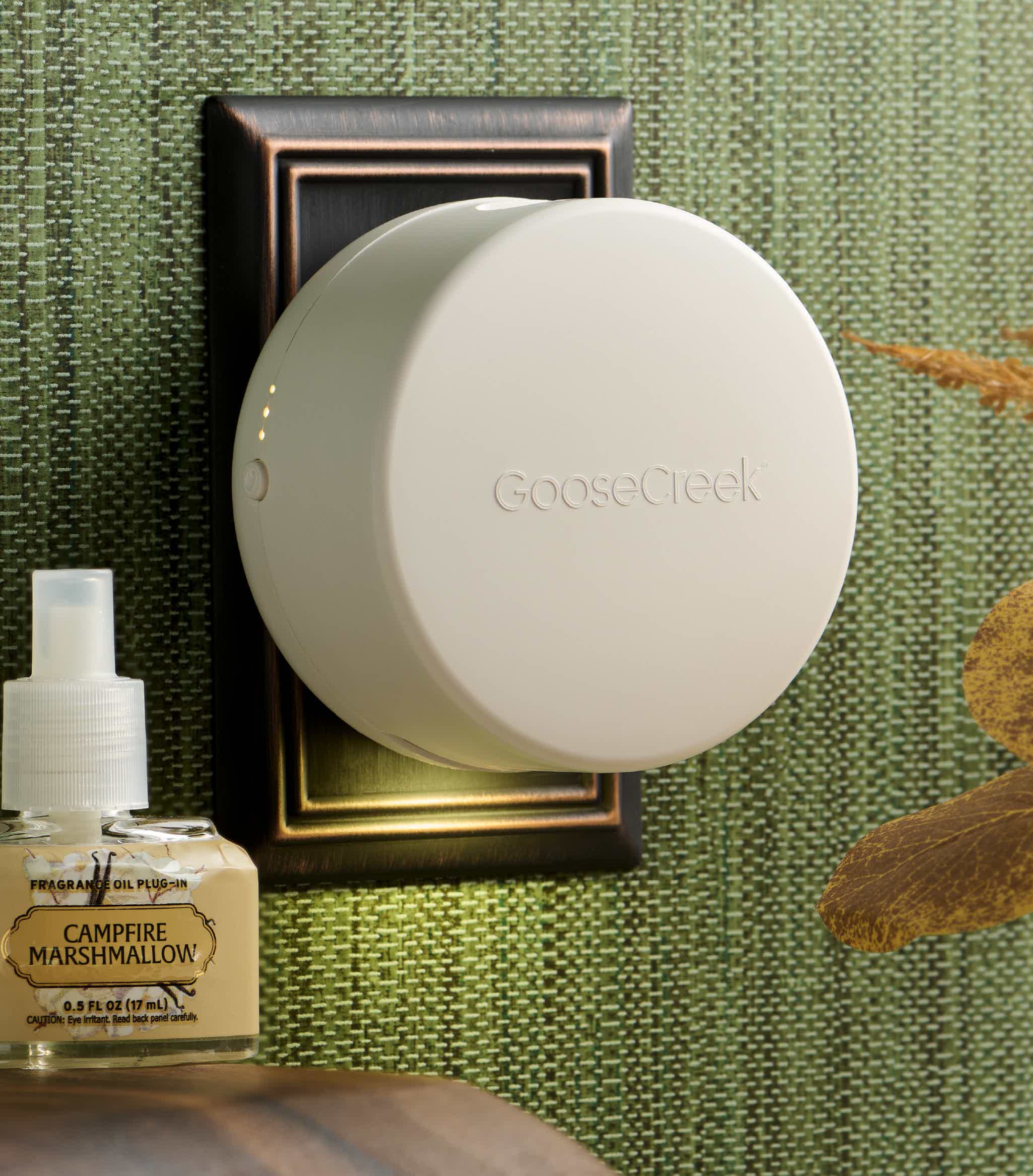 A white circular device mounted on a wall, next to a perfume bottle.