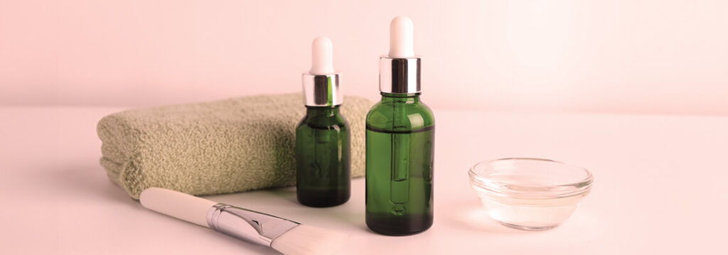 Two green bottles, a towel, and a small glass bowl on a table.