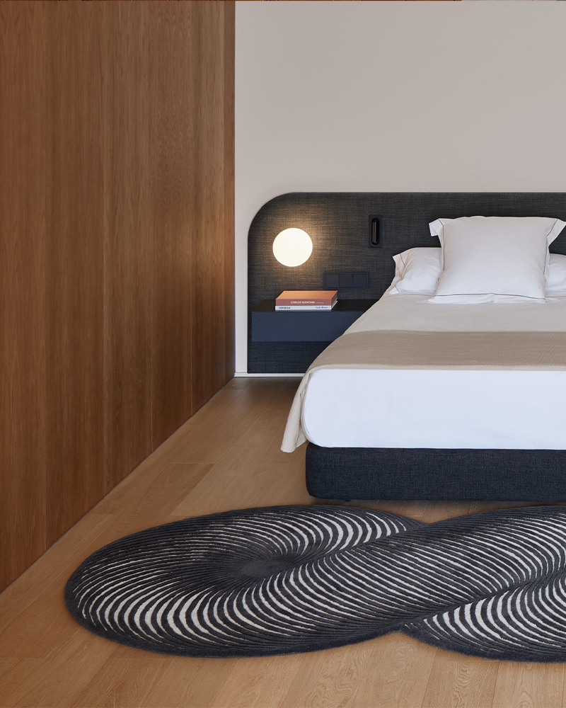 Modern bedroom with a bed, nightstand, and patterned GAN rug.