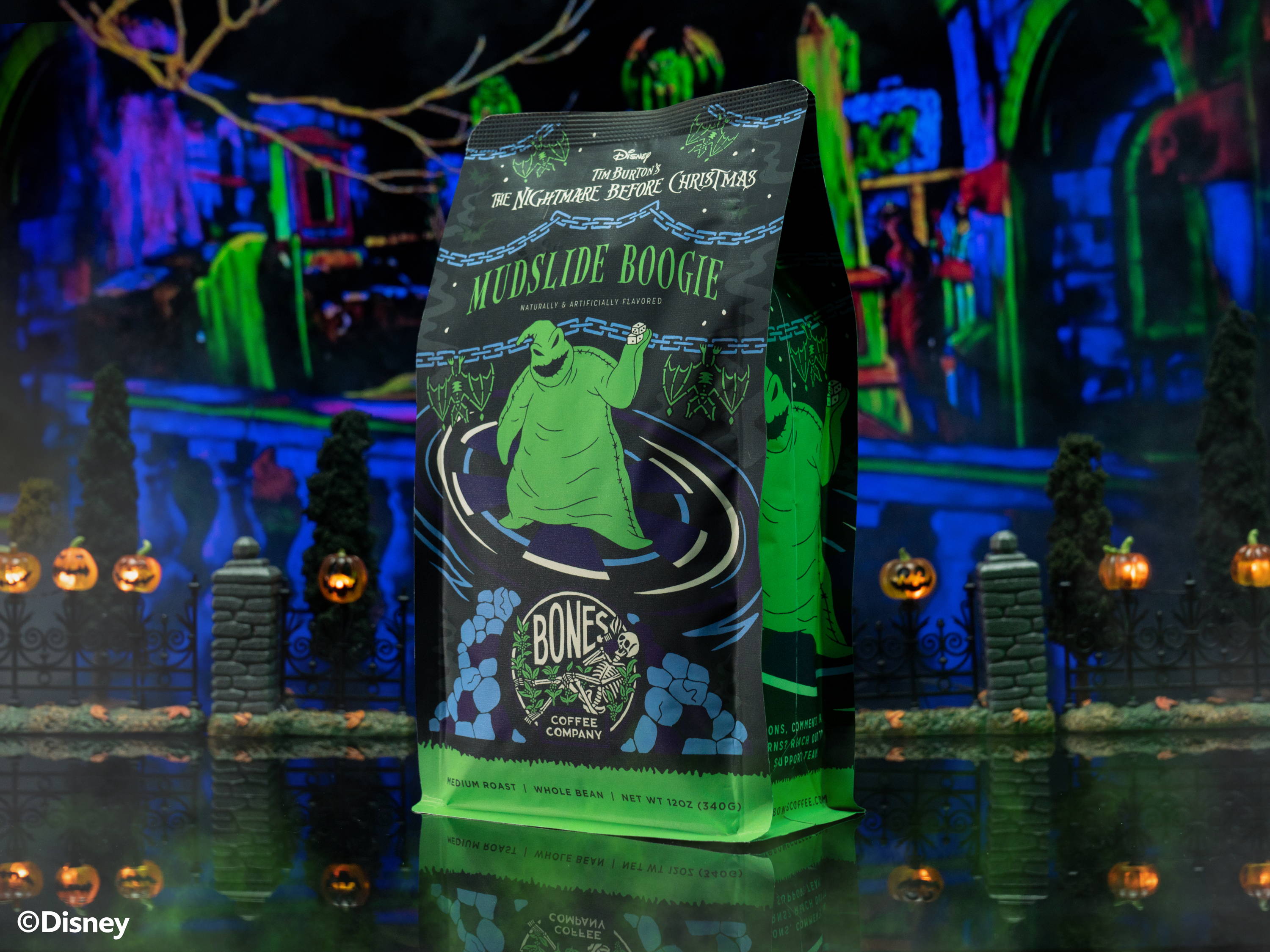 A 12 ounce bag of Bones Coffee Company Mudslide Boogie coffee. Its flavor is mudslide and it has Oogie Boogie on the art. The bag is inside a toy graveyard.
