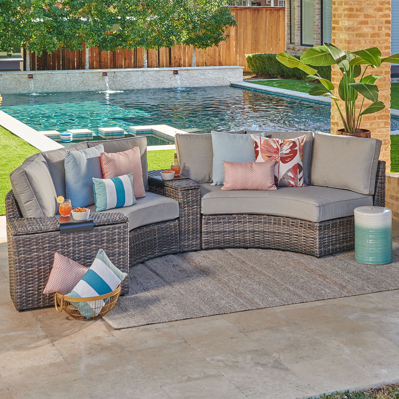 Outdoor sectional sofa with cushions beside a swimming pool and plants.