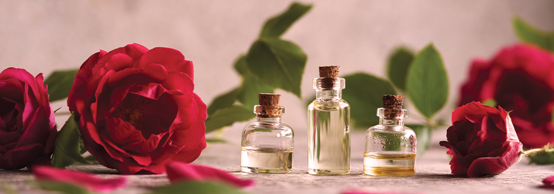 Bottles of oil with red roses on a soft background.