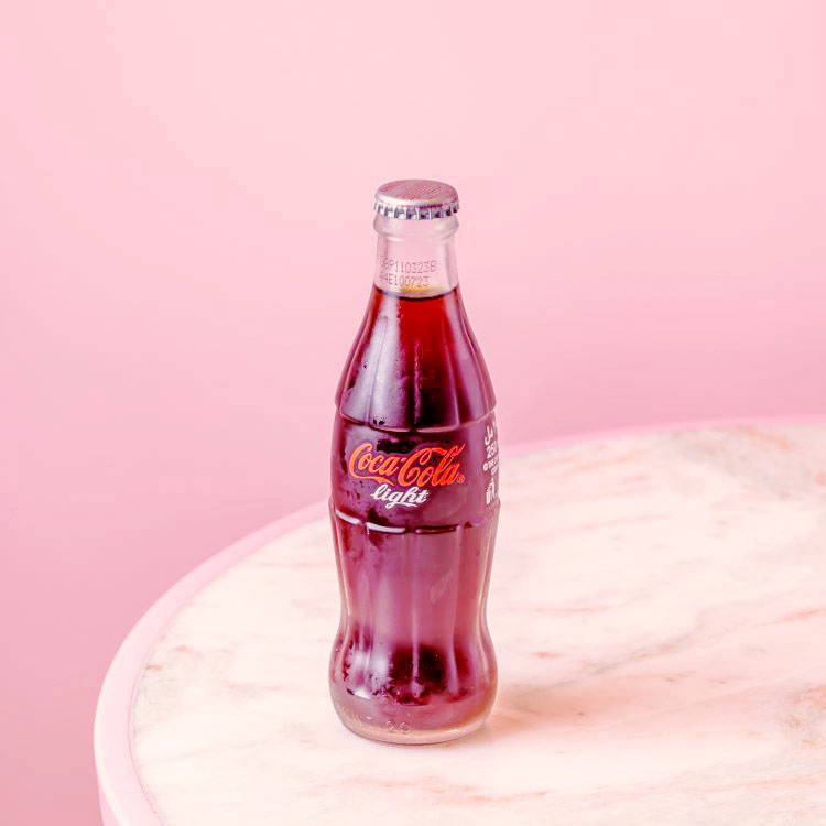 Diet Coke in glass bottle with pink background