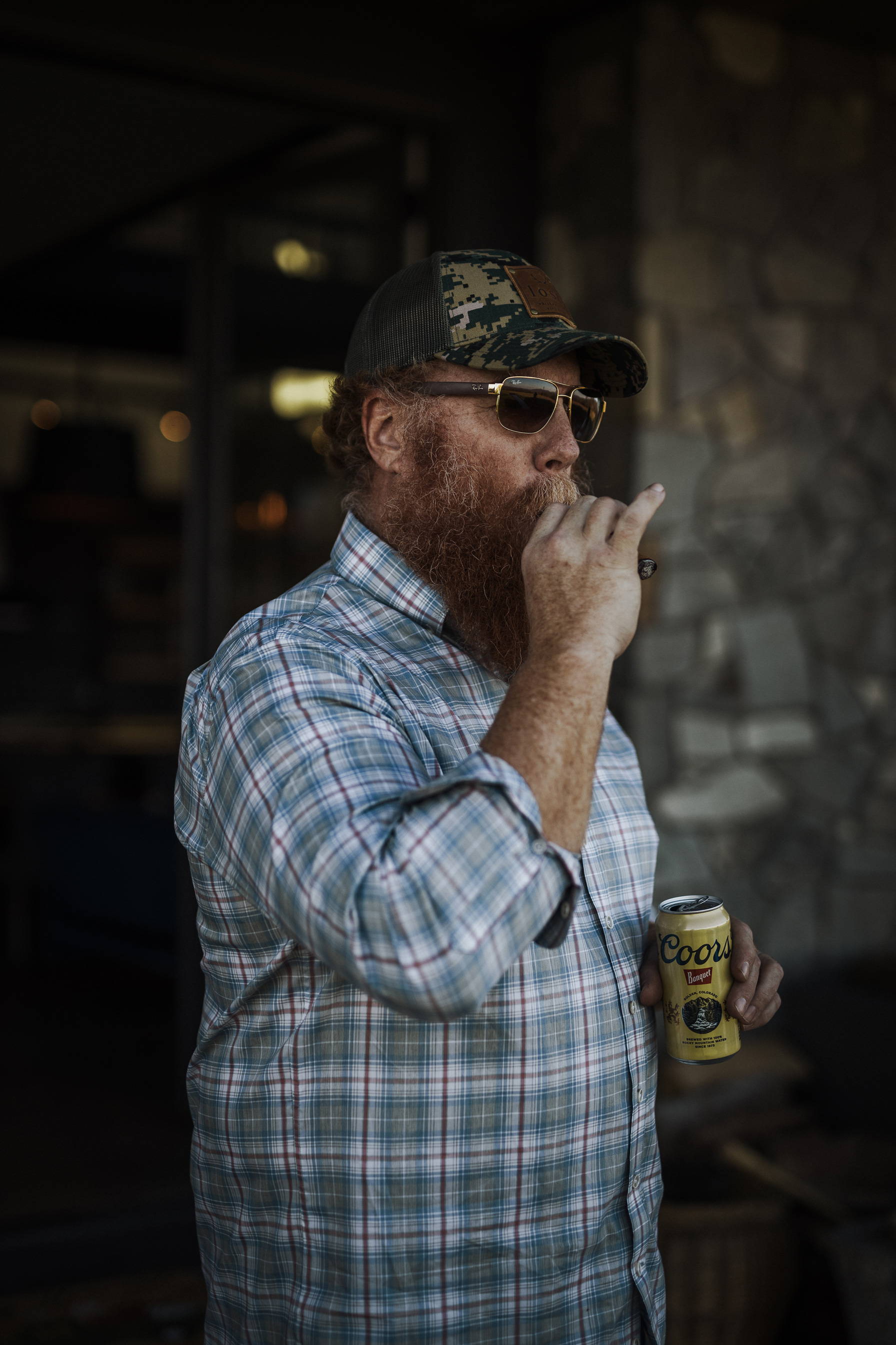 A man smoking a cigar and holding a Coors Light.