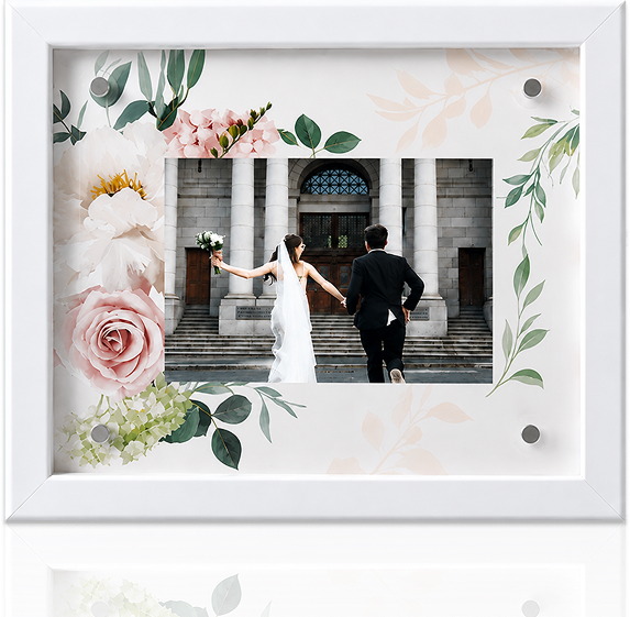 A couple holding hands in wedding attire, framed with floral decorations.