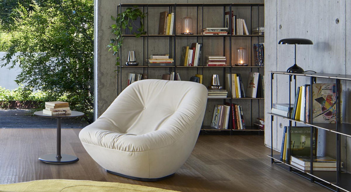 Cozy white chair next to a bookshelf and small side table.