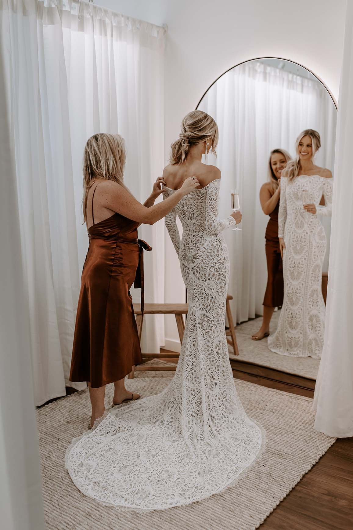 Bride holding champagne with stylist in bridal showroom