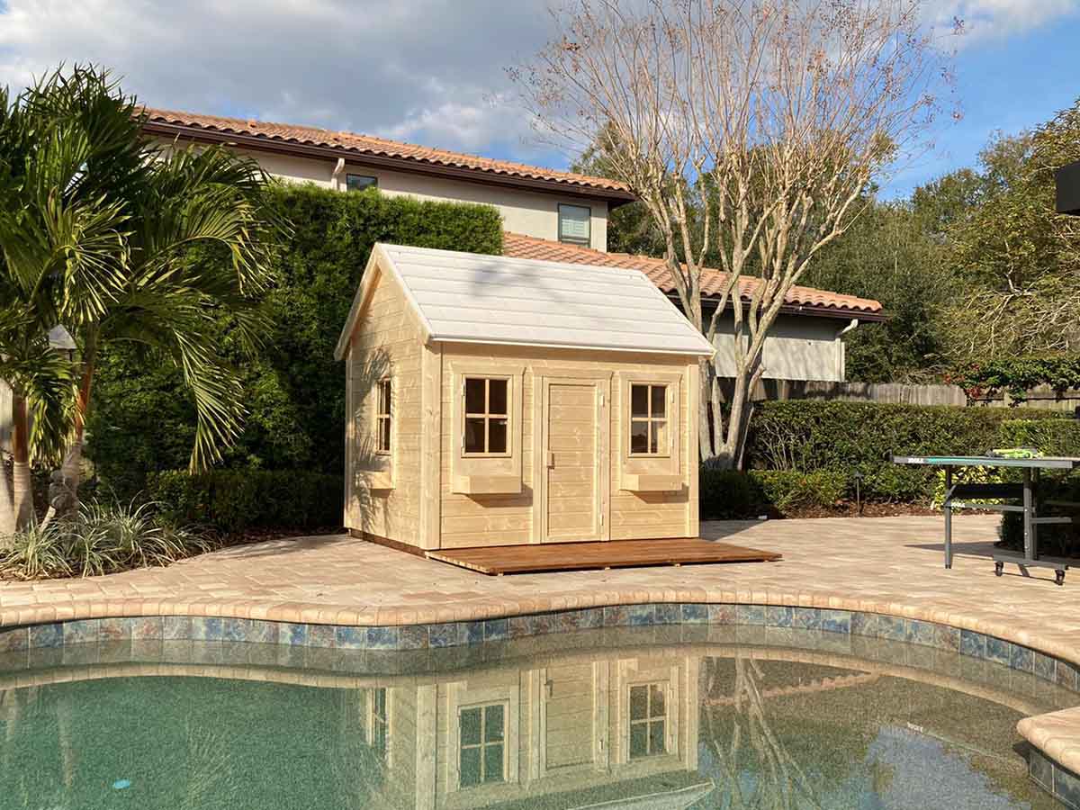 Kids 2 hours assembly Playhouse Natural Wonder with metal roof and wooden terrace in a backyard by WholeWoodPlayhouses