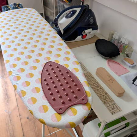 ironing board zone in a sewing room with the ironing board, steam iron and other ironing and pressing tools