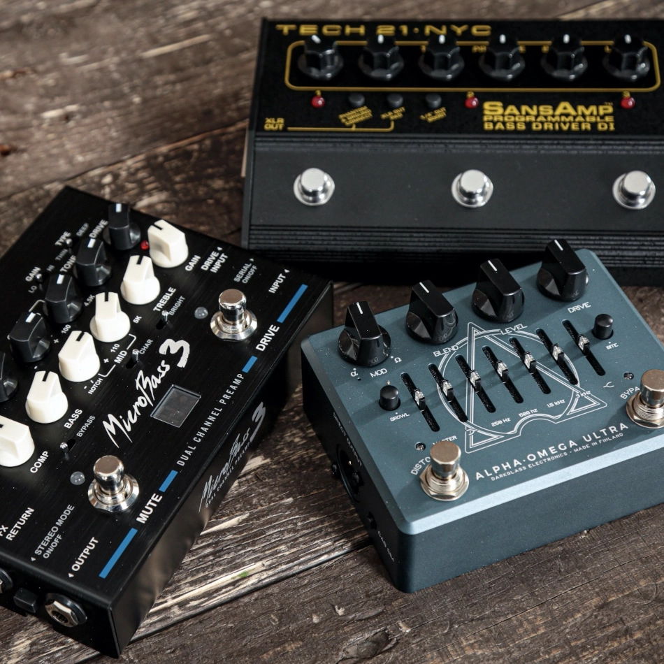 Three bass preamp pedals on a wooden surface.